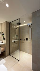 Sleek bathroom with glass shower, beige tiles, and contemporary fixtures.