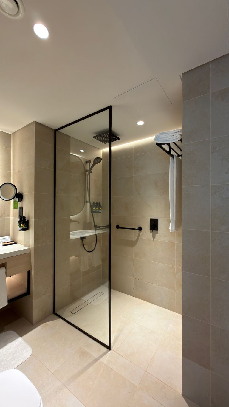 Sleek bathroom with glass shower, beige tiles, and contemporary fixtures.